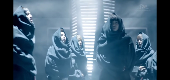 엑소 데뷔 뮤직비디오 "우리 엄마" (2012)를 연상시키는 로브를 입은 멤버들을 보여준다. "중세 승려" 연세대학교 신학과 교수 Shamah J. Kunda에 따르면. [SCREEN CAPTURE]