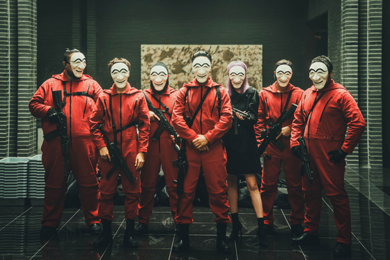 A band of thieves, fully clad in red suits and hahoetal (traditional Korean masks) take over the mint of a unified Korean Peninsula in an attempt to steal 4 trillion won ($3 billion) in “Money Heist: Korea — Joint Economic Area.” [NETFLIX]