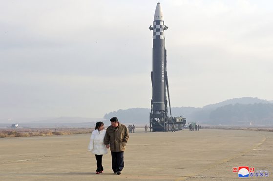 김정은 북한 노동당 위원장이 19일 평양국제공항에서 화성-17형 대륙간탄도미사일(ICBM)형 발사를 참관하기 위해 딸의 손을 잡고 있는 모습을 북한 중앙통신이 공개한 사진에서 밝혔다.  통신사(KCNA) 토.  김씨의 자녀 중 한 명이 대중에 공개된 것은 이번이 처음이다. [KCNA]